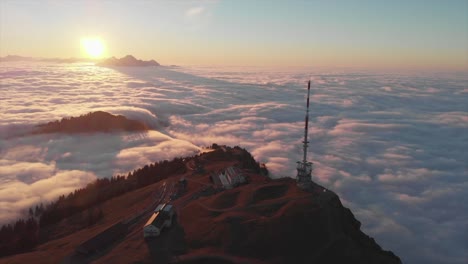 Sunset-drone-view-to-mountain-top-surrounded-by-a-sea-of-clouds