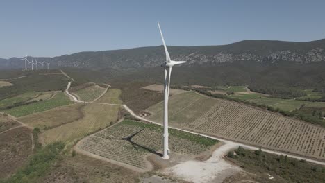 Windmills-spin-in-aerial-view-of-valley-vineyards-in-French-Pyrenees