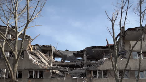 Dead-trees-stand-in-front-of-a-hotel-that-was-hit-by-a-cruise-missile,-destroying-a-large-section-of-the-building-during-the-Russian-invasion-of-Ukraine