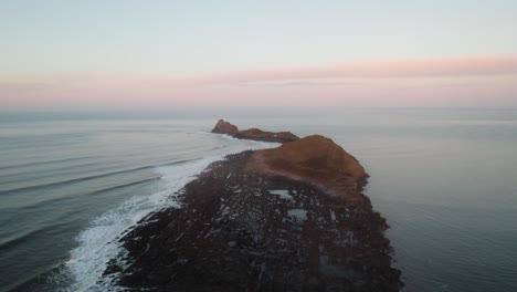 AERIAL:-Wide-circle-of-Worm's-Head-during-sunrise,-Rhossili-Gower,-4k,-Drone