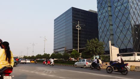 Blick-Auf-Die-Fahrzeuge,-Die-Sich-An-Einem-Sommertag-In-Hyderabad-Auf-Der-Autobahn-Vor-Den-Hohen-Bürogebäuden-Bewegen