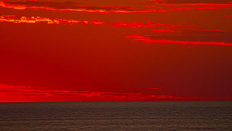 Half-circle-sun-rising-in-the-horizon-on-a-red-fiery-sky-background,-time-lapse