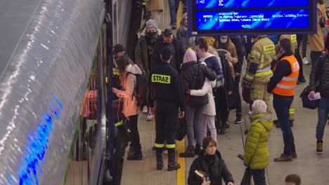 2022-Russian-invasion-of-Ukraine---Central-Railway-Station-in-Warsaw-during-the-refugee-crisis---firefighters-helping-people-enter-the-train
