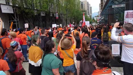 Demonstranten-Zum-Canada-Day-Stornieren-In-Orangefarbenen-T-Shirts,-Die-Mit-Fahnen-Und-Plakaten-Inmitten-Der-Pandemie-In-Kanada-Auf-Der-Straße-Spazieren