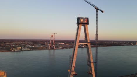 Forwarding-aerial-shot-of-the-Gordie-Howe-Bridge-under-construction,-Suspension-tower-with-crane,-Detroit---Michigan