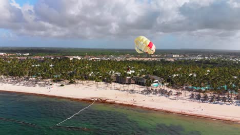 People-parasailing-in-Dominican-Republic,-Punta-Cana-resort,-extreme-sport,-drone-aerial-view