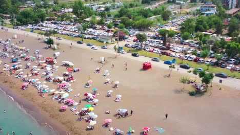 Bunte-Luftaufnahme-Eines-Typischen-Europäischen-Strandes-Namens-Adrasan-Voller-Menschen-Und-Sonnenschirme-An-Einem-Heißen-Sommertag-Entlang-Der-Türkischen-Küste