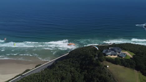 Drone-shot-of-Wilderness-beach-in-South-Africa---drone-is-circling-around-a-hill-full-of-paragliders