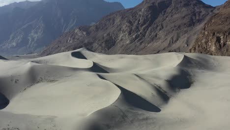 Luftdrohne-Fliegt-An-Einem-Sonnigen-Sommertag-An-Sanddünen-In-Der-Kalten-Wüste-Von-Skardu,-Pakistan-Vorbei,-Mit-Der-Schroffen-Bergkette-Im-Hintergrund