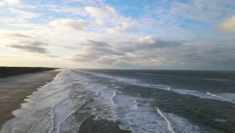 Aerial-view-of-rolling-waves-and-sunrise-at-the-ocean-close-to-Løkken-by-the-North-Sea,-Denmark