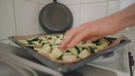 Man-placing-chunks-of-zucchini-evenly-on-a-baking-sheet