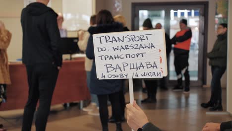 Hombre-Que-Sostiene-Una-Pancarta-Con-Las-Palabras-Que-Transportan-A-Cuatro-Personas-A-Varsovia-En-Polaco-Y-Ucraniano-Para-Refugiados-De-Ucrania
