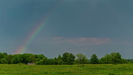 Statische-Ansicht-Eines-Wunderschönen-Regenbogens-über-Grünem-Grasland-In-Einer-Ländlichen-Landschaft-Im-Frühling