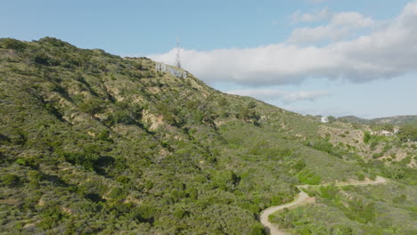 Hollywood-Ahead,-Drone-Flying-Towards-Famous-Hollywood-Sign-in-Green-Hollywood-Hills