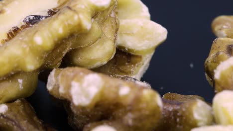 Close-up-shot,-skin-of-peeled-walnuts-rotating-over-black-surface-background