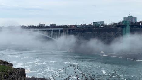 Rainbow-bridge-in-niagara-falls---United-states-and-Canada-border-bridge-over-Niagara-River-close-up-telephoto-as-mist-from-waterfall-passes---Zoomed-bridge-going-to-USA-and-Canada-national-border