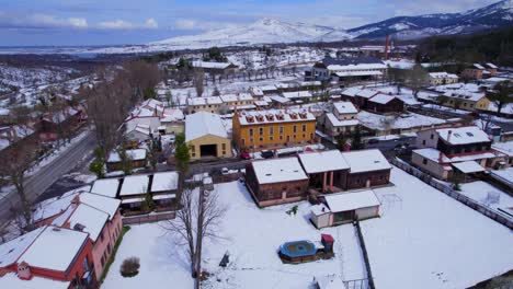 Low-cinematic-aerial-over-the-snow-covered-buildings-and-streets-of-Spains-Pradera-in-the-midst-of-winter