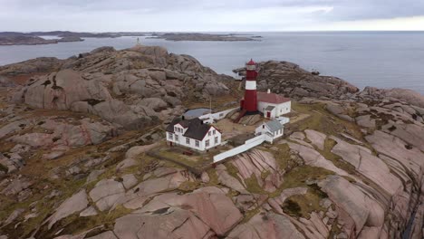 Beautiful-island-Ryvingen-with-active-lighthouse-and-lighthousekeepers-house-outside-Mandal-Norway---Aerial-slowly-rotating-and-moving-from-close-to-overview-of-location