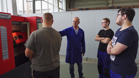 Teacher-explaining-how-to-use-a-Computer-Numerical-Control-milling-machine-to-a-small-group-of-young-male-students-at-vocational-high-school-in-Slovakia
