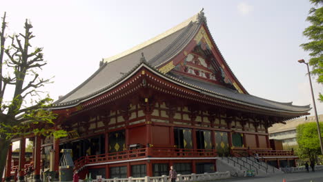 ASAKUSA,-TOKYO,-JAPAN,-circa-April-2020:-people-walking-in-authentic-Japanese-temple-with-gorgeous-craftmanship-decoration-on-roof-and-wall-on-sunny-spring-day