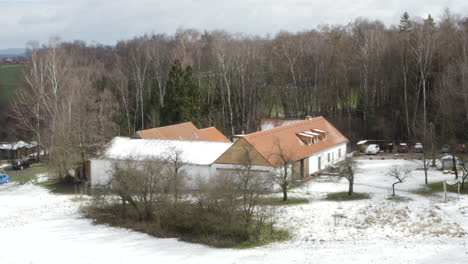 Farmhouse-secluded-in-tree-grove-in-early-winter-countryside,-drone