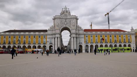 Slow-motion-view-of-Commerce-Square-in-Lisbon,-Portugal-filled-with-tourists-visiting-the-capitol-city,-historic-landmarks-and-buildings