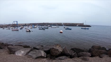 Pan-to-the-Right-with-Ships-Docked-in-a-Harbor-with-Black-Rocks