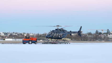 A-Bell-Helicopter-with-Spinning-Rotor-on-a-Mobile-Platform-on-a-Snowy-Airport