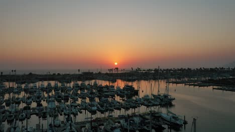 Drone-Ascend-Over-Marina-With-Boats-At-Dusk-Setting-On-The-Seascape