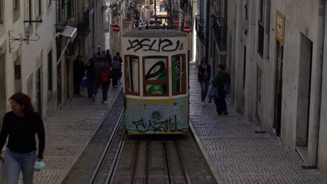 Elevator-da-Bica,-19th-century-cable-railway-riding-up-and-down-a-quaint-street-with-a-sharp-incline,-Lisbon,-Portugal