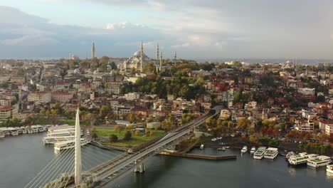 Große-Luftaufnahme-Eines-Zuges,-Der-An-Einem-Farbenfrohen-Und-Lebendigen-Sonnenaufgangsmorgen-In-Istanbul,-Türkei,-Die-Halic-U-Bahn-Brücke-Und-Den-Bosporus-überquert,-Mit-Der-Hagia-Sophia-In-Der-Ferne-Auf-Einem-Hügel