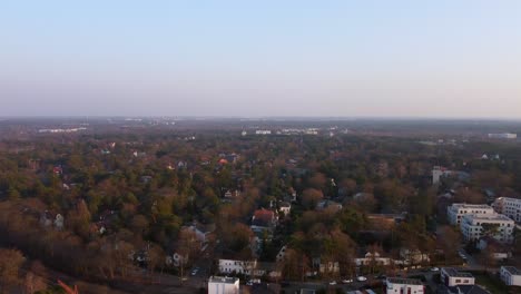 Perfect-aerial-view-flight-panorama-overview-drone-footage-at-sunset-over-a-small-suburb-of-Berlin-in-the-woods-on-a-forest-lake-in-Germany