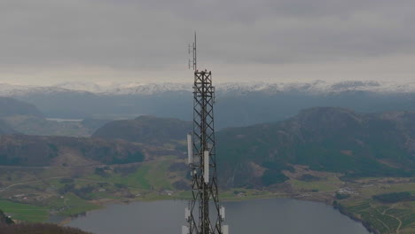 Close-up-drone-shot-orbiting-a-telephone-5G-mast-with-mountain-backdrop,-Scandinavia