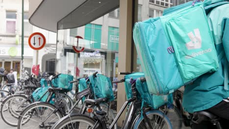 Deliveroo-courier-waiting-outside-the-store-on-the-urban-city-streets-of-Belgium