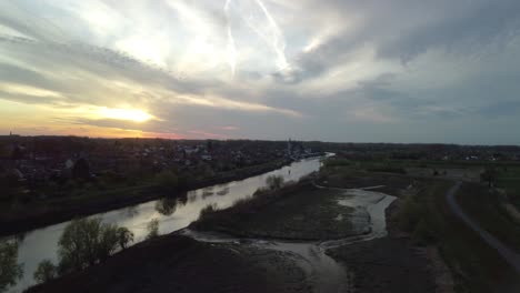 A-drone-pans-over-the-river-Schelde-and-a-city-at-sunset
