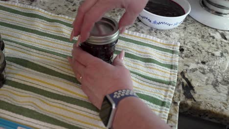 Putting-lids-and-seals-on-jars-of-homemade-berry-jam---slow-motion
