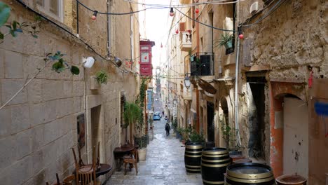 Lonely-person-walking-in-narrow-street-of-Valletta-downtown,-handheld-tilt-up-view