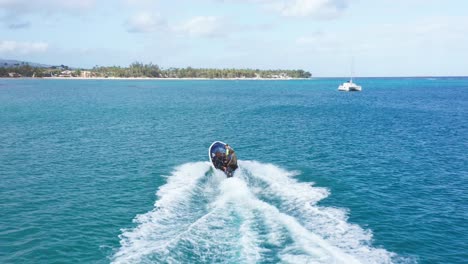 Aerial-tracking-shot-of-speedboat-cruising-over-blue-colored-Caribbean-Sea-during-sunlight