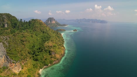 aerial-landscape-panning-right-across-Ko-Kai-Island-and-Ko-Poda-in-the-distance-surrounded-by-stunning-turquoise-blue-ocean-and-lush-green-forests-on-a-sunny-summer-day-in-Krabi-Thailand
