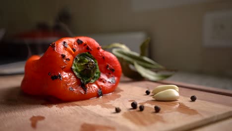 Roasted-Red-Bell-Pepper-On-Wooden-Board-With-Black-Peppercorns-And-Peeled-Garlic