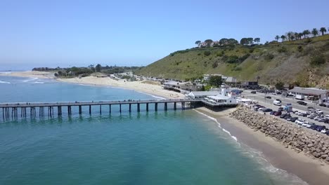 Malibu-Pier-with-white-Restaurant,-Highway-and-Parking-Lot