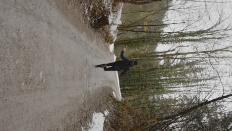 Young-man-with-short-dark-hair-and-black-jacket-running-on-a-road-in-the-woods-on-a-cloudy-day