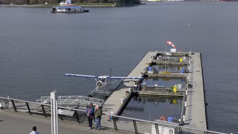 Erwachsenes-Paar-Posiert-Für-Ein-Foto-Im-Hafen-Von-Vancouver-Mit-Angedocktem-Wasserflugzeug-Im-Hintergrund