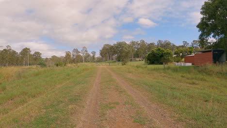 Point-of-View-of-hikers-bushwalking-old-rail-line,-raised-edges,-gravel-pathway,-old-sheds-and-trees-along,-Brisbane-Valley-Rail-Trail,-Qld-4K