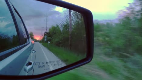 Reflection-side-rearview-car-mirror-in-morning-on-road-at-sunset-or-sunrise