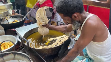 Ein-Alter-Mann,-Der-Auf-Einem-Freiluftmarkt-In-Bangladesch-Handgefertigte-Spiraljalebi-Herstellt