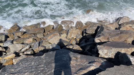 Shadow-of-a-man-looking-to-the-waves-crushing-on-rocks