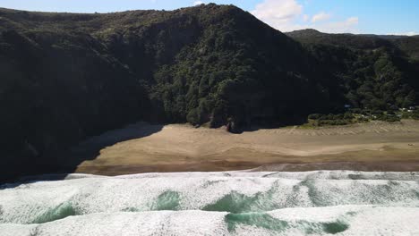Steep-mountain-ranges-and-hiking-trails-along-black-sand-beach-on-New-Zealand's-West-coast