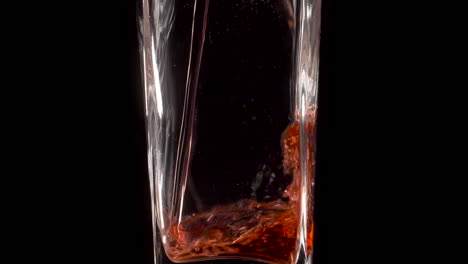 Red-drink-poured-into-long-glass,-isolated-shot-with-black-background