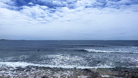 Slo-Mo-Pan-view-of-surfers-and-swimmers-at-Moffat-Beach,-Sunshine-Coast-Queensland-Aus